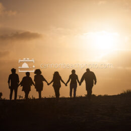 Silhouetted Family Hand in Hand on the Beach